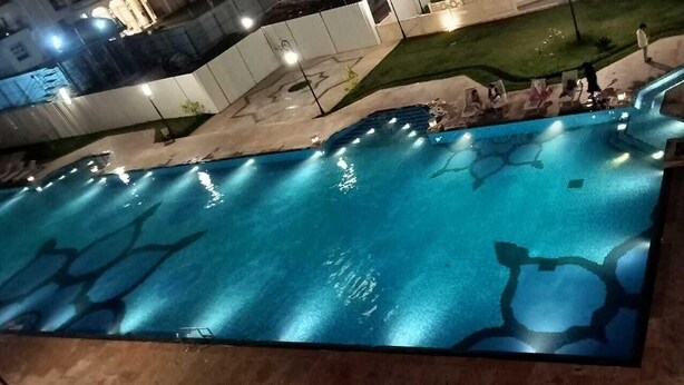 Ein Schwimmbecken mit einem außergewöhnlichen Design, umgeben von Liegestühlen und einem kleinen Wasserfall.