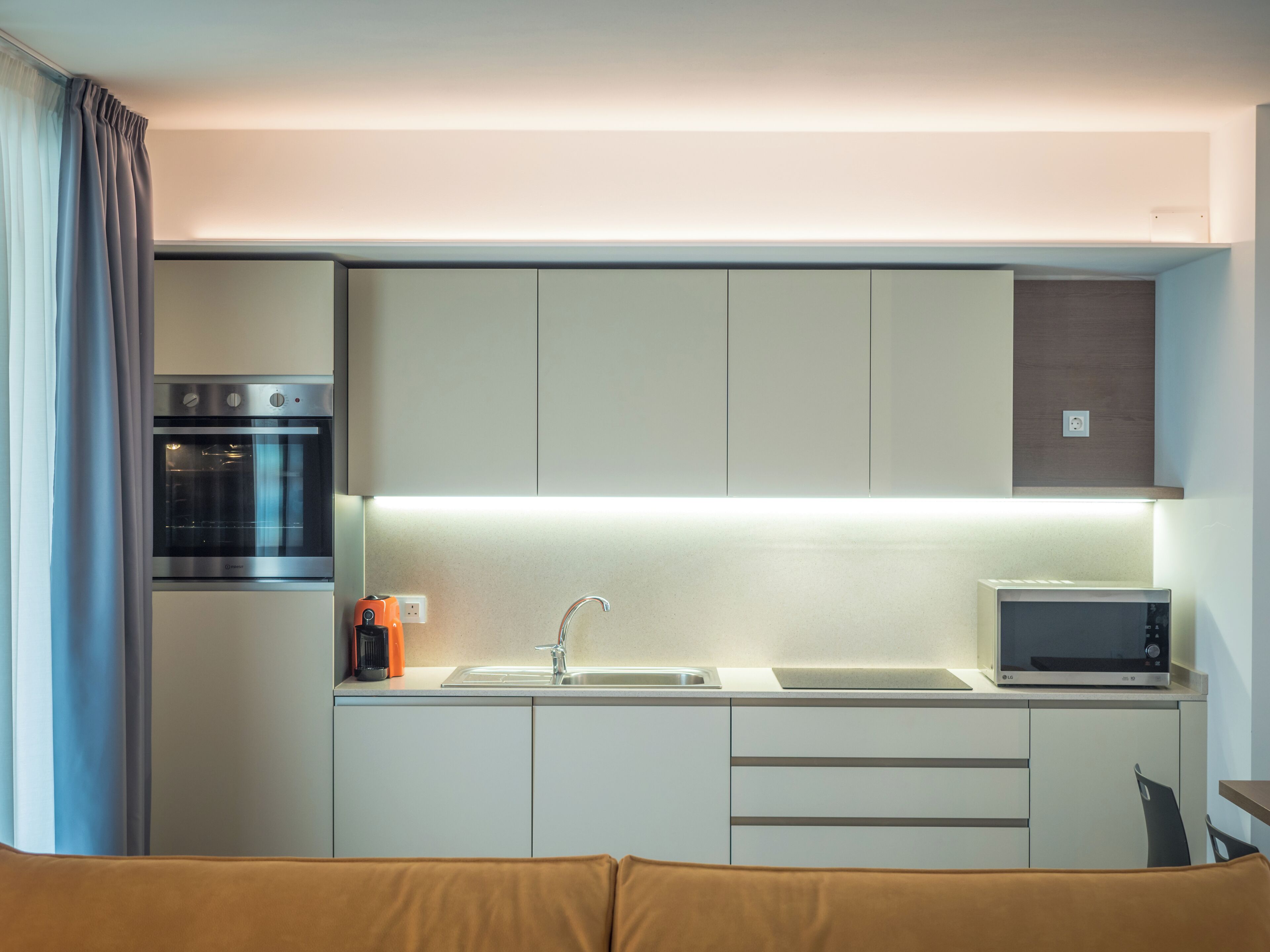 A modern kitchen with a built-in oven, microwave, and sink.