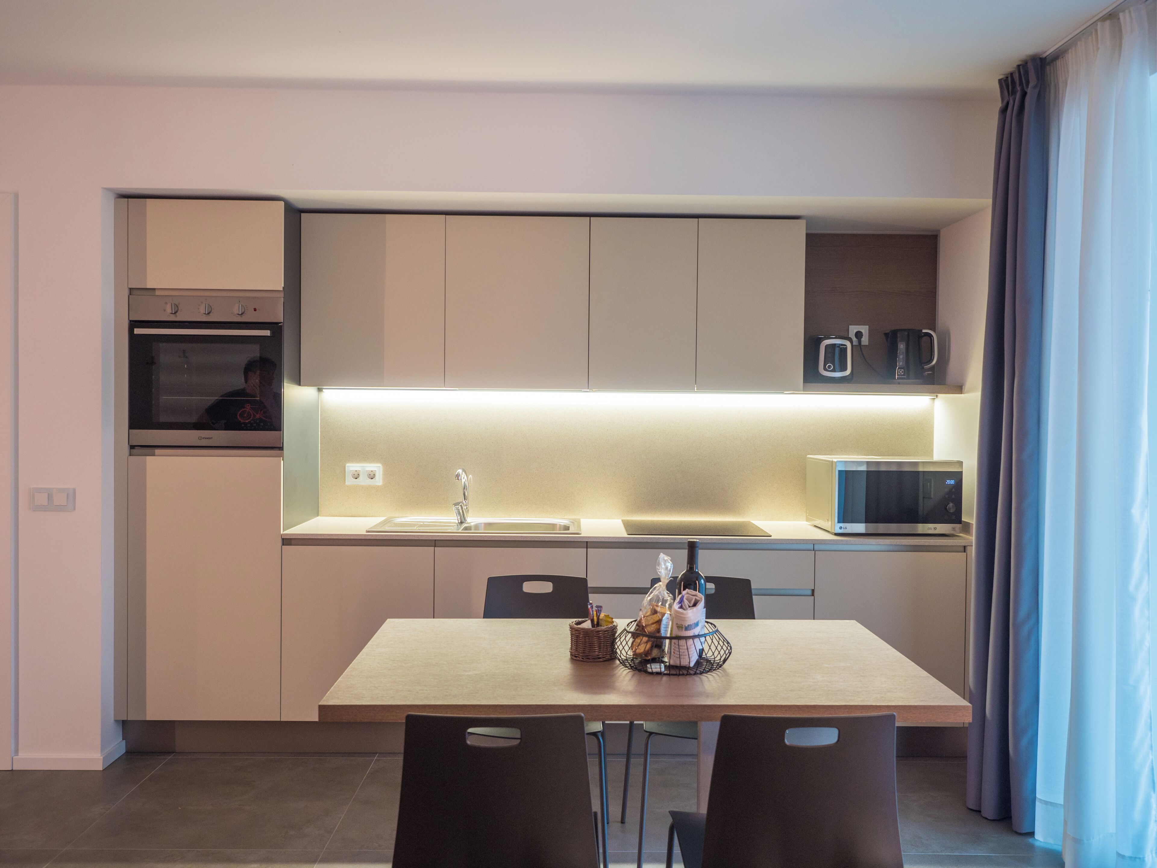 A modern kitchen with a built-in oven, microwave, and a dining area with a table and chairs.