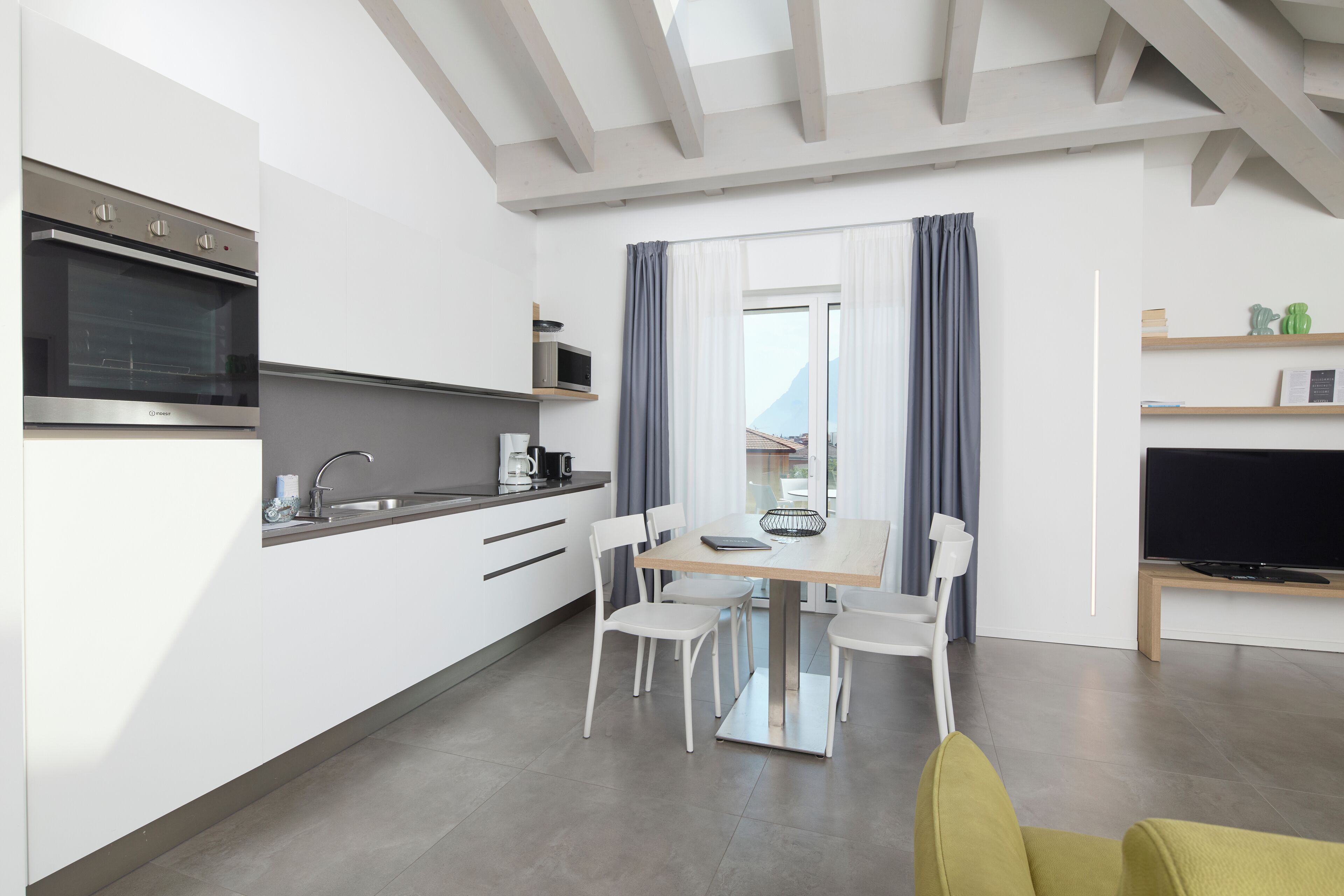 A modern kitchen with built-in appliances, a dining area with a table and chairs, and a television on a stand.
