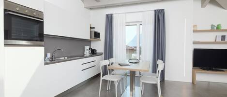A modern kitchen with built-in appliances, a dining area with a table and chairs, and a television on a stand.