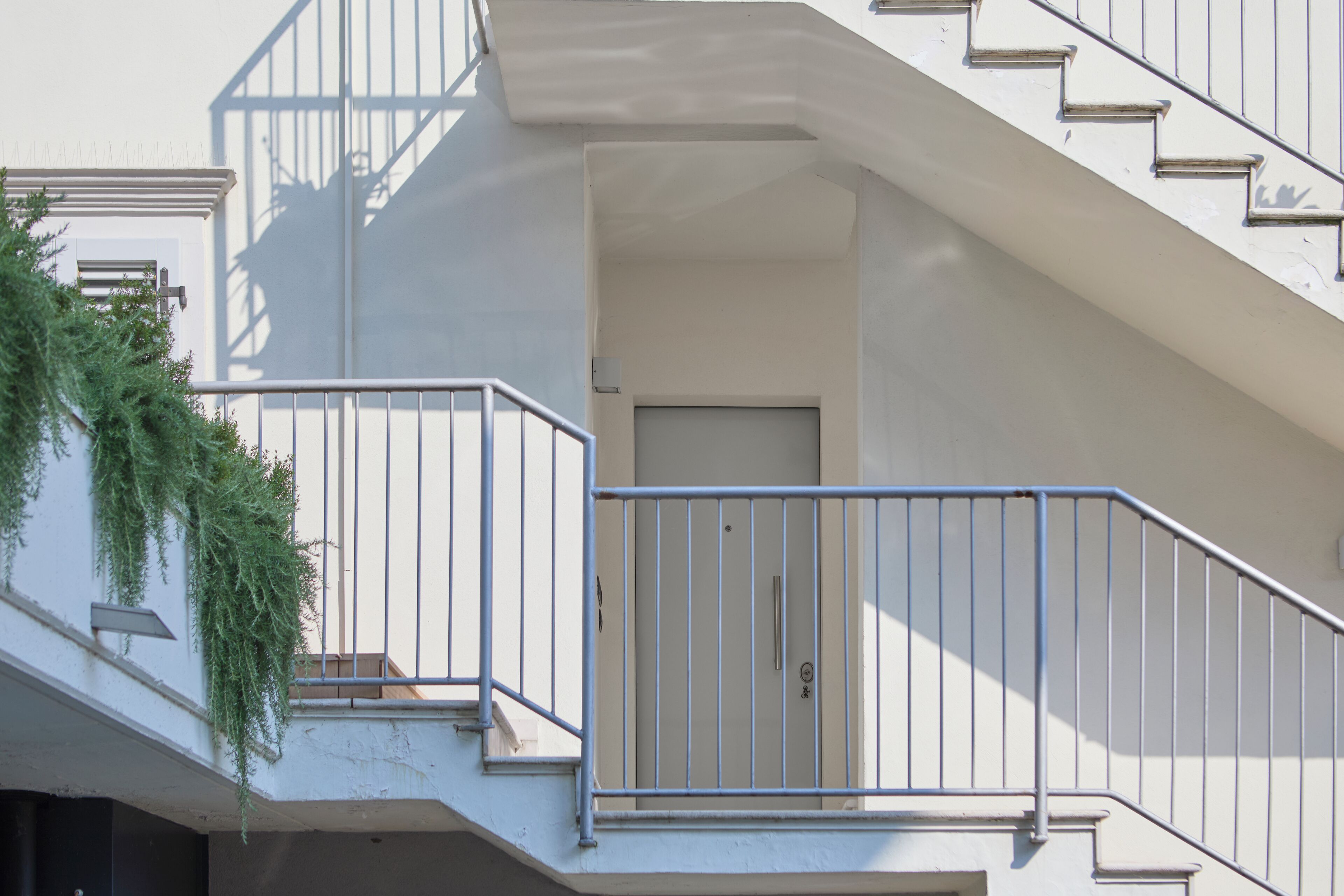 A multi-level residential building with a staircase, a door, and a metal railing.