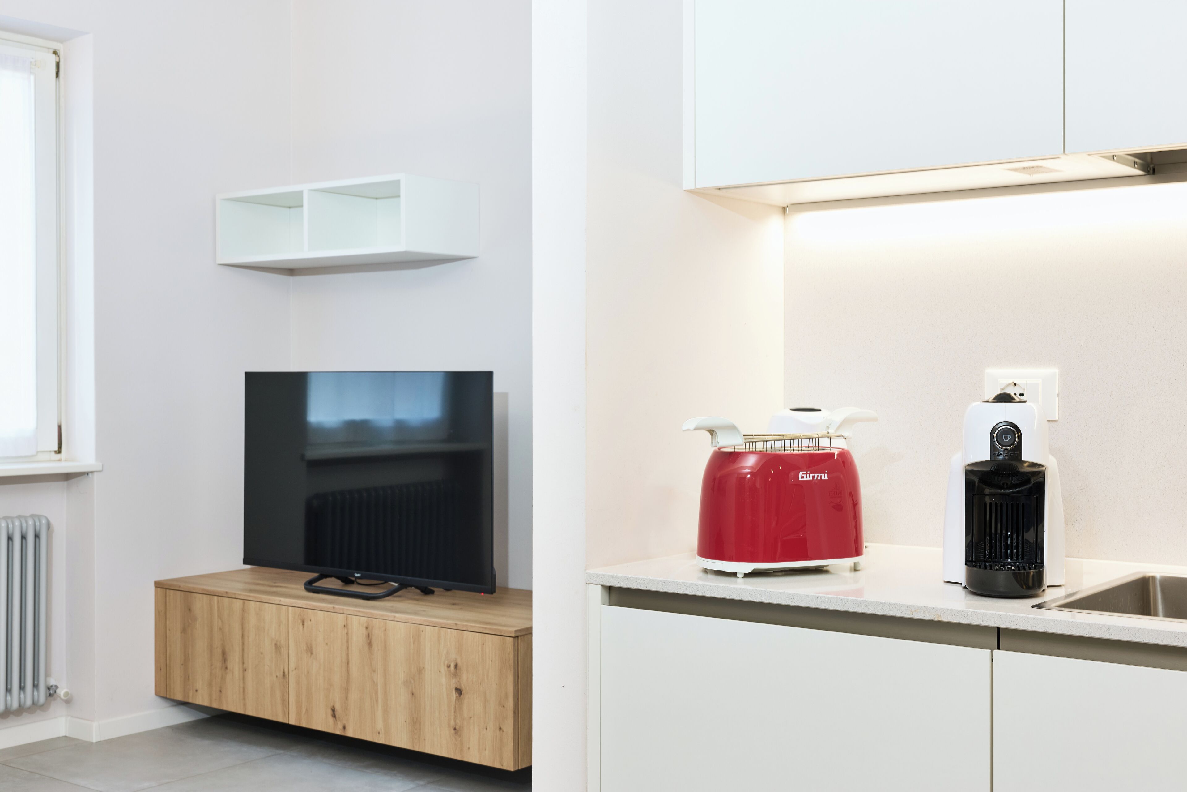 Een moderne keuken met een ingebouwde televisie, een rode waterkoker en een koffiezetapparaat.