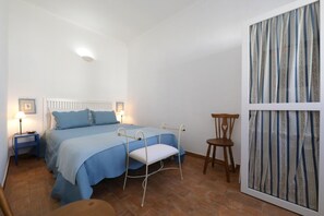 A bedroom with a bed, bedside tables, a chair, and a curtain.