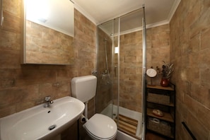 A bathroom with a sink, toilet, and glass-enclosed shower.