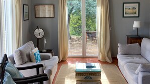 A living room with a ceiling fan, a sofa, a coffee table, and a view through a glass door to an outdoor patio.