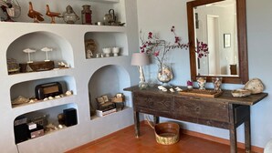 A room with a wooden dresser, shelves with various items, a mirror, and a tiled floor.