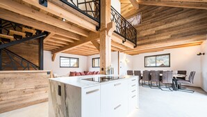 Una cocina moderna con una isla de mármol, vigas de madera y un comedor con sillas y una mesa.