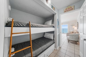 A bunk bed room with a ladder, a small desk, and a chair.