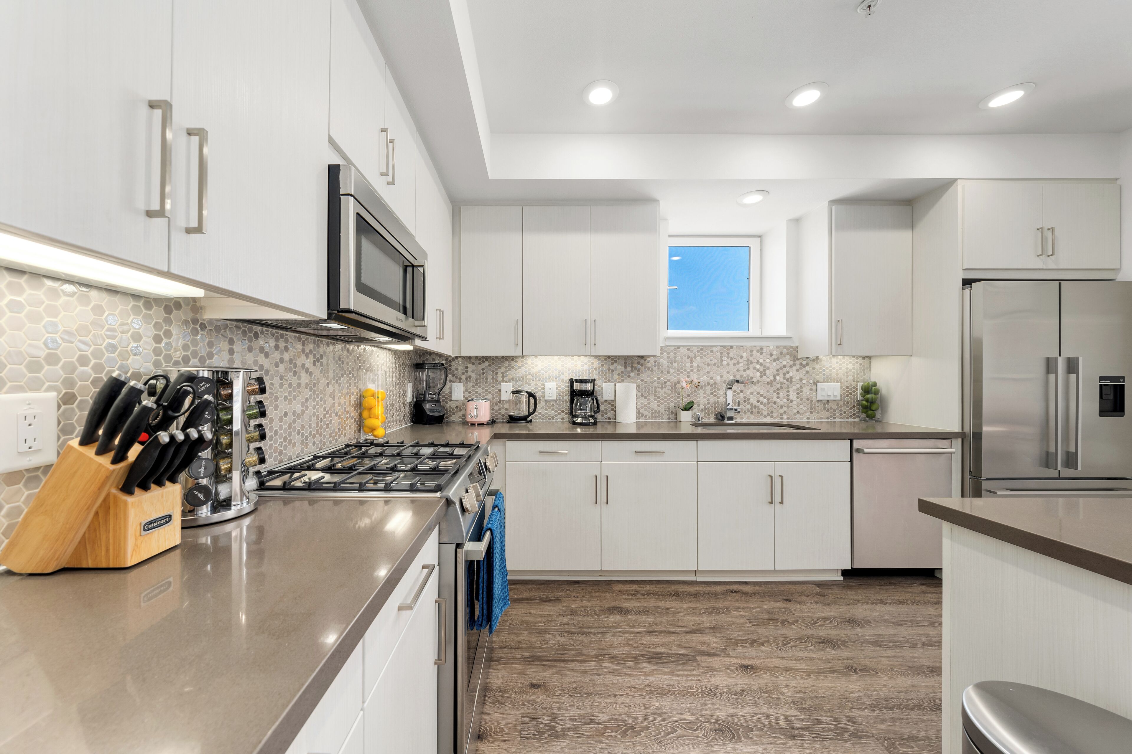 A modern kitchen with white cabinets, stainless steel appliances, and a wooden countertop.