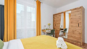 Ein Hotelzimmer mit Bett, Schreibtisch, Stuhl, Kleiderschrank und einem Fenster mit Vorhängen.