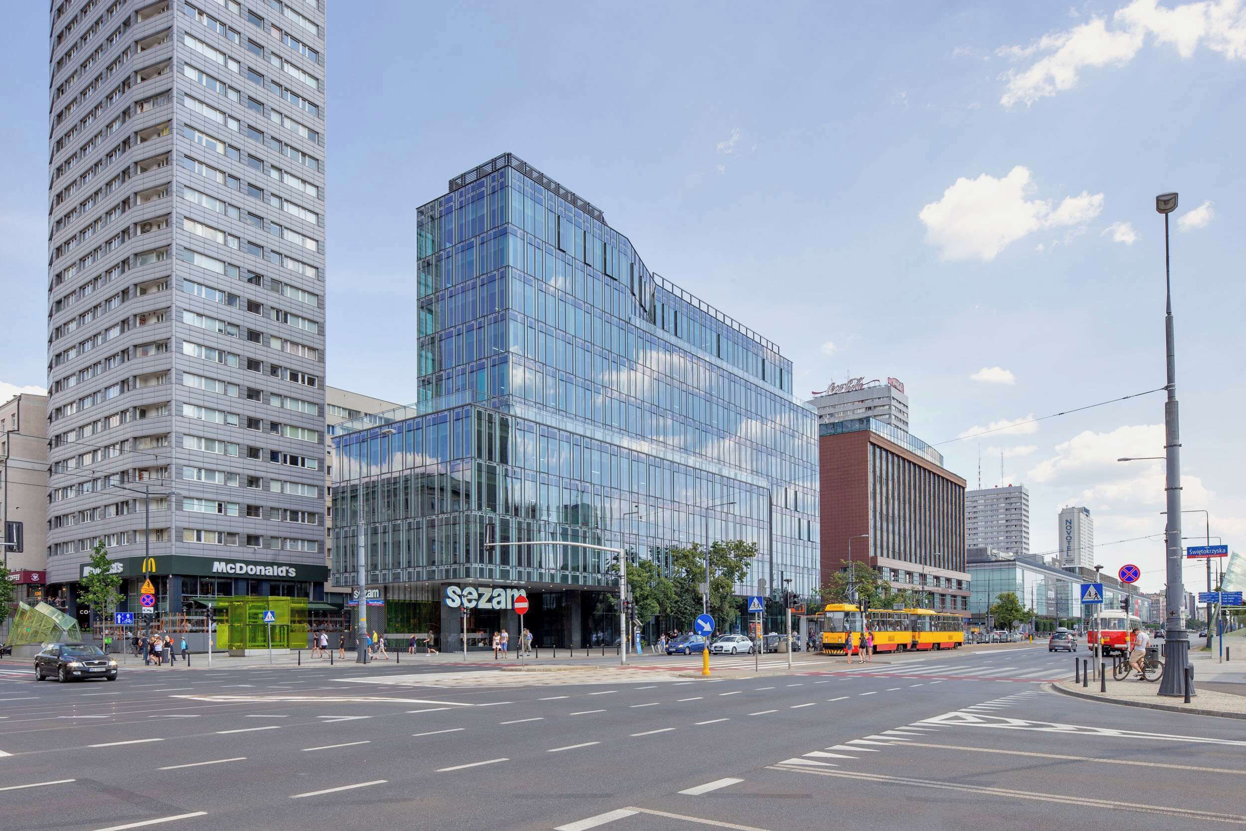A modern building with a glass facade, a McDonald's restaurant, and a bus stop.