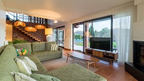 Un salon moderne avec un canapé, un téléviseur et un escalier menant à un niveau supérieur.