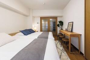 Habitación de hotel con dos camas, un escritorio y una silla.