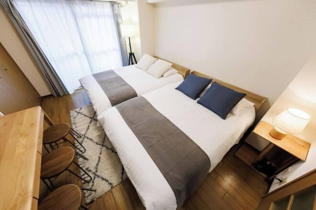 A hotel room with two beds, a desk, and a chair.