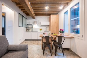 A modern kitchen with wooden beams, a dining area with two chairs, and a window with a view.