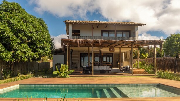A two-story house with a pool, wooden deck, and outdoor seating area. - Casinha Praia do Espelho (Porto Seguro)