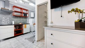 A modern kitchen with a microwave, red shelving, and a TV mounted on the wall. - Studio Apartment 'Economy  For Two in Lagos' with Shared Pool, Wi-Fi and Air Conditioning (Lagos)
