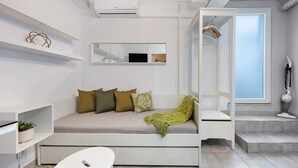 A modern room with a sofa bed, a small table, a mirror, and a window. - Studio Apartment 'Economy  For Two in Lagos' with Shared Pool, Wi-Fi and Air Conditioning (Lagos)