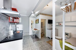Une cuisine moderne avec un plan de travail noir, un coin repas blanc et un téléviseur encastré.