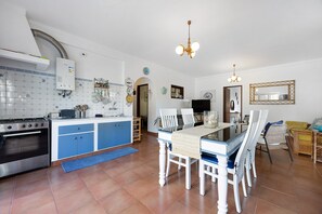 A kitchen with a stove, cabinets, and a dining area with chairs and a table. - Apartment 'Tranquility Villa Fonte Coberta' with Shared Pool, Wi-Fi and Air Conditioning (Lagos)