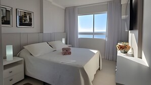 Une chambre d’hôtel moderne dotée d’un grand lit, d’un ventilateur de plafond, d’une télévision et d’une fenêtre offrant une vue agréable.