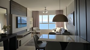 Une chambre d’hôtel moderne dotée d’un coin repas, d’une grande fenêtre offrant une vue dégagée, d’un téléviseur à écran plat fixé au mur et d’un ventilateur de plafond.