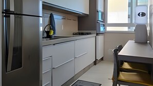Une cuisine moderne dotée d’appareils électroménagers en acier inoxydable, de meubles blancs et d’un coin repas avec une table et des chaises.