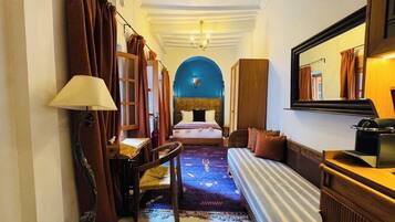 Una habitación de hotel con cama, sofá, escritorio, lámpara y espejo.