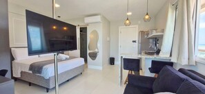 Una habitación de hotel moderna con cama, televisión, zona de comedor y ducha.