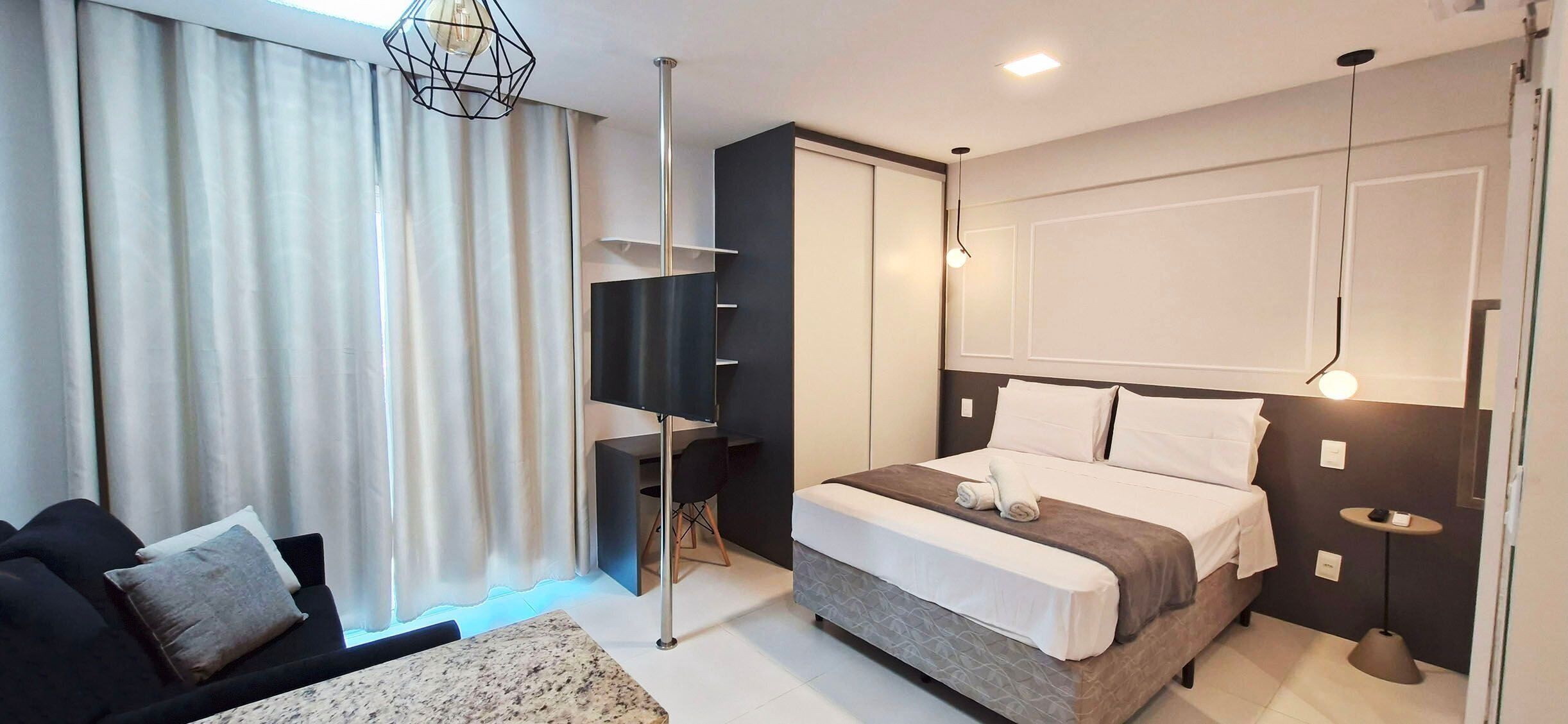 A modern bedroom with a bed, a desk, and a sofa.