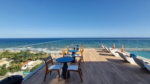 Eine Terrasse mit Tischen und Stühlen mit Blick auf den Ozean.
