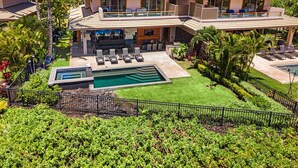 A large house with a swimming pool, outdoor seating, and lush greenery.