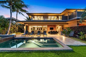 Una casa moderna de dos pisos con piscina, mobiliario exterior y un jardín bien cuidado.