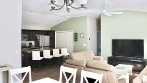 Ein modernes Wohnzimmer mit Sofa, Fernseher und Essbereich mit Stühlen und Tisch.