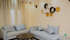 A living room with two sofas, a coffee table, and decorative wall art. - Igitego Hotels (Kigali)
