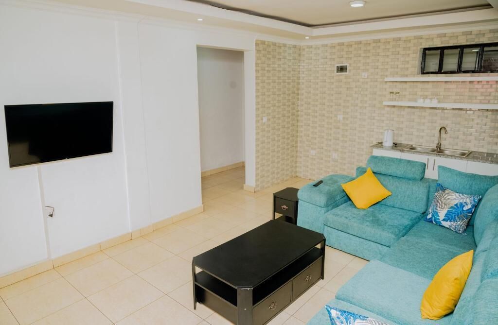 Een moderne woonkamer met een bank, een salontafel en een flatscreen televisie aan de muur.