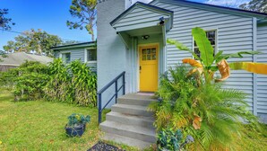 Uma casa com porta amarela, um pequeno alpendre e uma escadaria que leva à entrada.