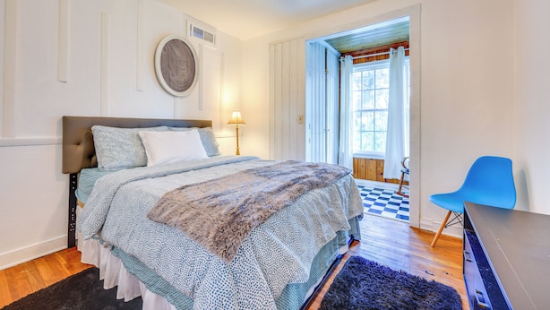 Quarto com cama, cadeira, abajur e ventilador de teto.