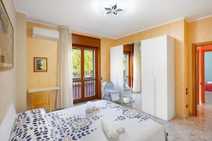Ein Schlafzimmer mit Bett, Schreibtisch, Stuhl, Kleiderschrank und einem Balkon.