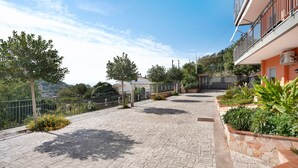 A paved pathway with a stone border, a metal fence, and greenery.