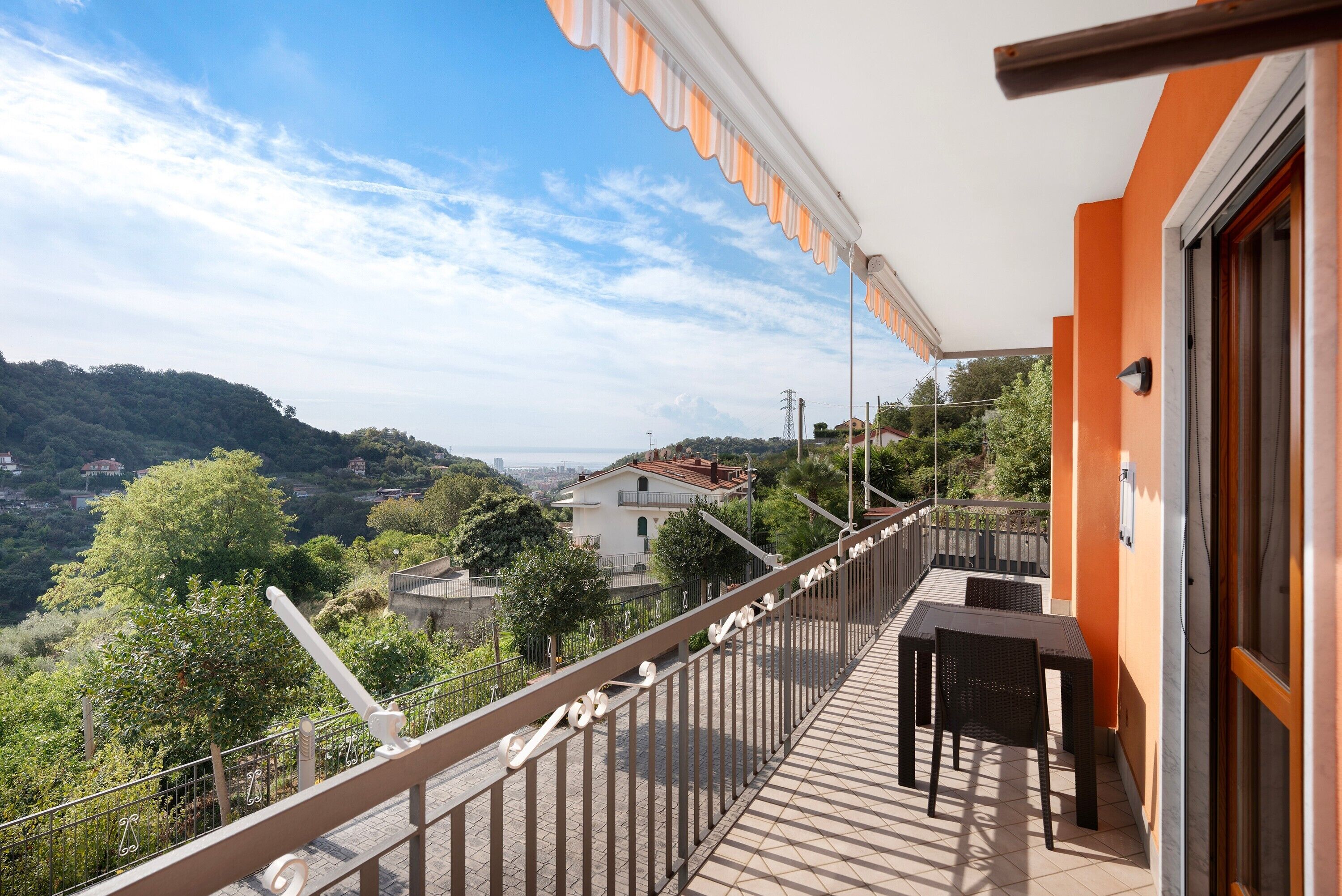 Un balcon donnant sur une colline, avec une table et des chaises.