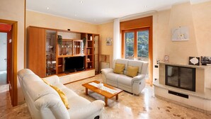 A living room with a sofa, a coffee table, a television, and a fireplace.