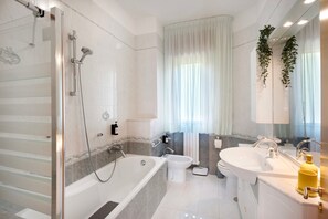 Ein modernes Badezimmer mit einer Glasdusche, einer freistehenden Badewanne, einem Standwaschbecken und einer Toilette.
