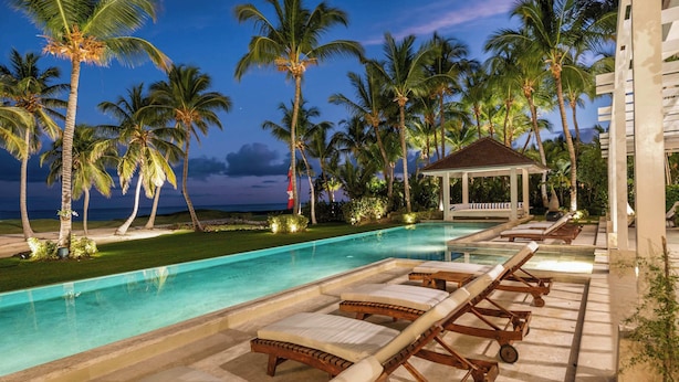 A poolside area with lounge chairs, palm trees, and a gazebo.