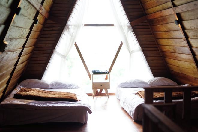 A room with two beds, a wooden bench, and a small table.