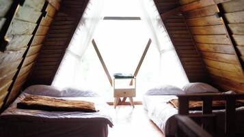 A room with two beds, a wooden bench, and a small table.