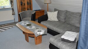 A living room with a wooden table, grey sofa, and a cabinet.