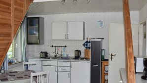 A kitchen with white cabinets, a coffee machine, and a refrigerator.