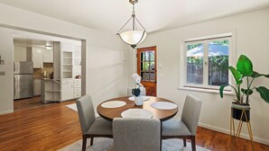 A dining area with a round table, four chairs, a chandelier, and a potted plant.